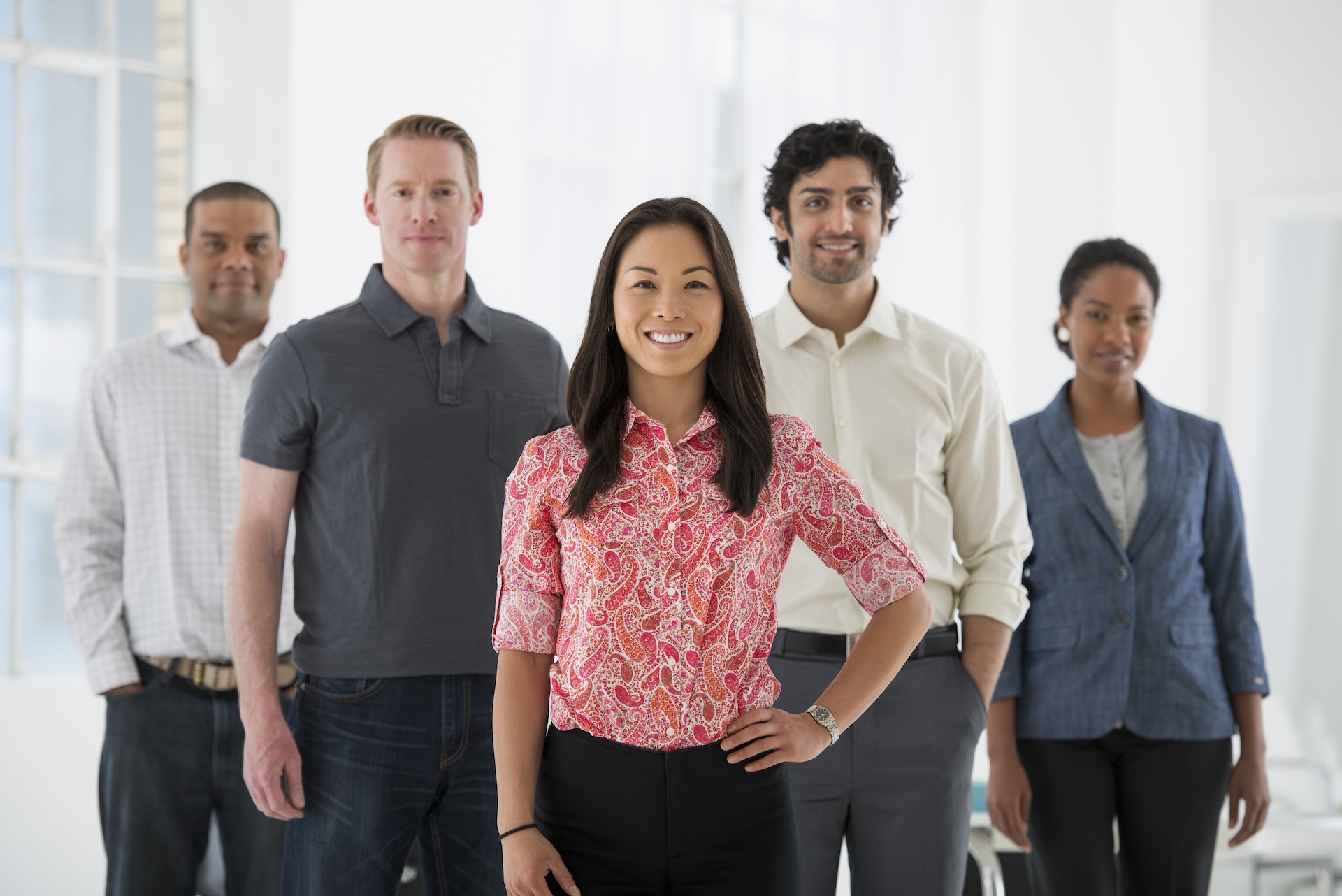 A diverse group of professionals standing together in an office, representing effective cross-cultural communication and teamwork